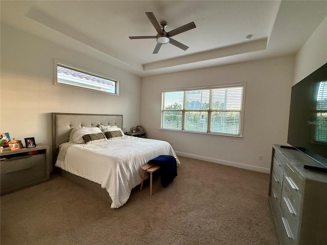 carpeted bedroom featuring a raised ceiling and ceiling fan