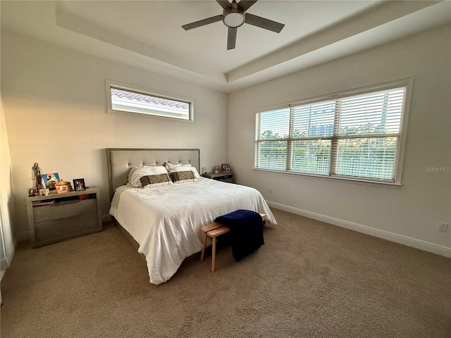 carpeted bedroom featuring ceiling fan and a tray ceiling