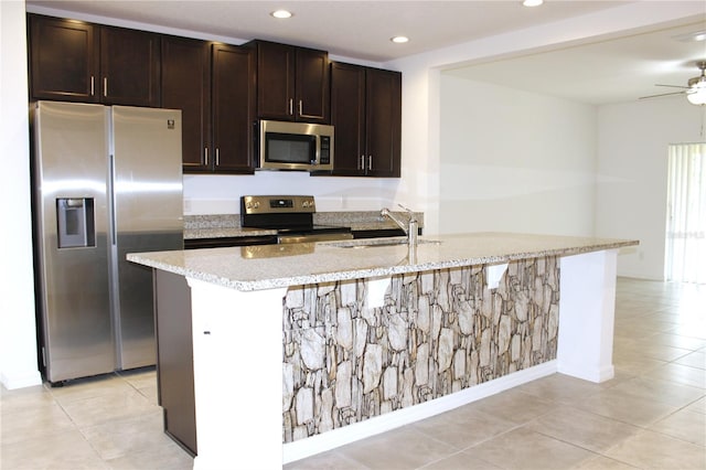 kitchen with dark brown cabinetry, appliances with stainless steel finishes, sink, and a center island with sink