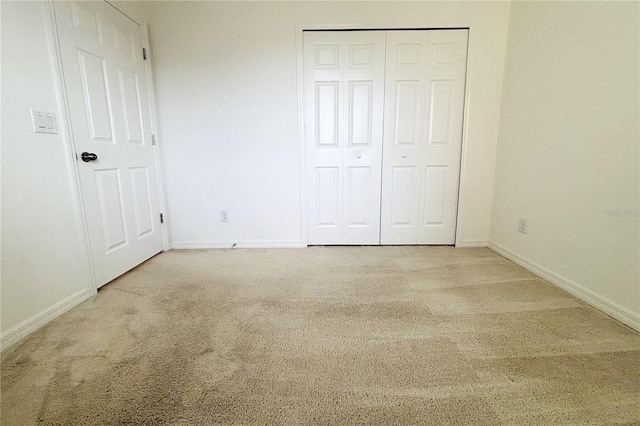 unfurnished bedroom featuring light colored carpet and a closet