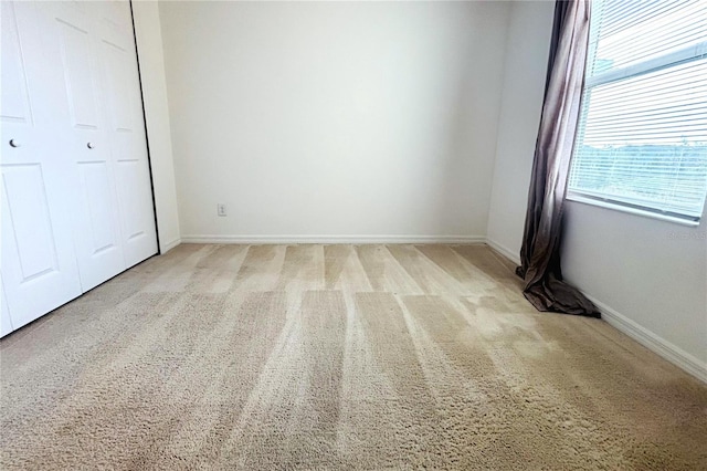 unfurnished bedroom with light colored carpet and a closet