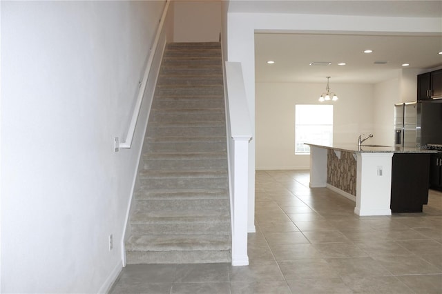 stairs with an inviting chandelier, tile patterned floors, and sink