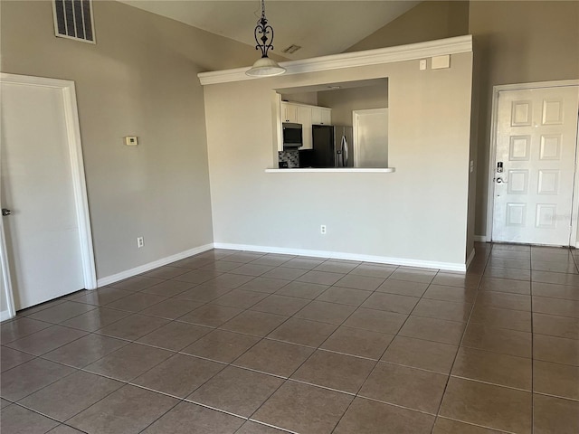 tiled spare room featuring vaulted ceiling