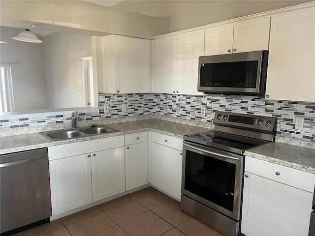 kitchen with sink, light tile patterned floors, white cabinets, stainless steel appliances, and backsplash