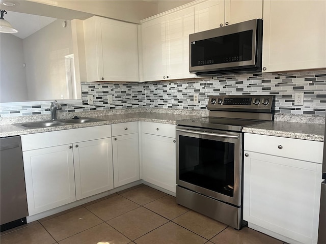 kitchen with appliances with stainless steel finishes, sink, white cabinets, and decorative backsplash