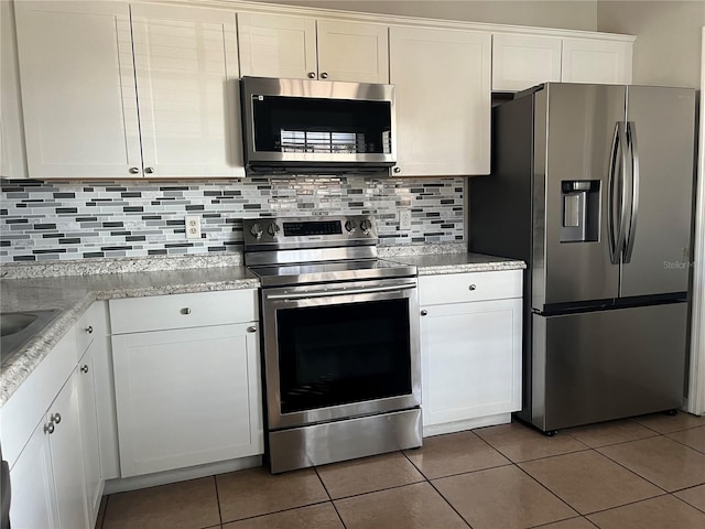 kitchen with stainless steel appliances, white cabinetry, tile patterned flooring, and backsplash