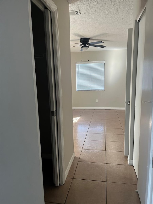 hallway with light tile patterned floors and a textured ceiling