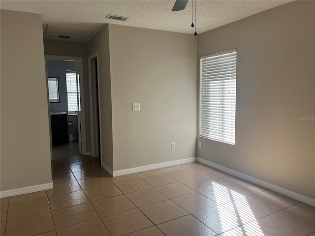 spare room featuring ceiling fan, plenty of natural light, a textured ceiling, and light tile patterned floors