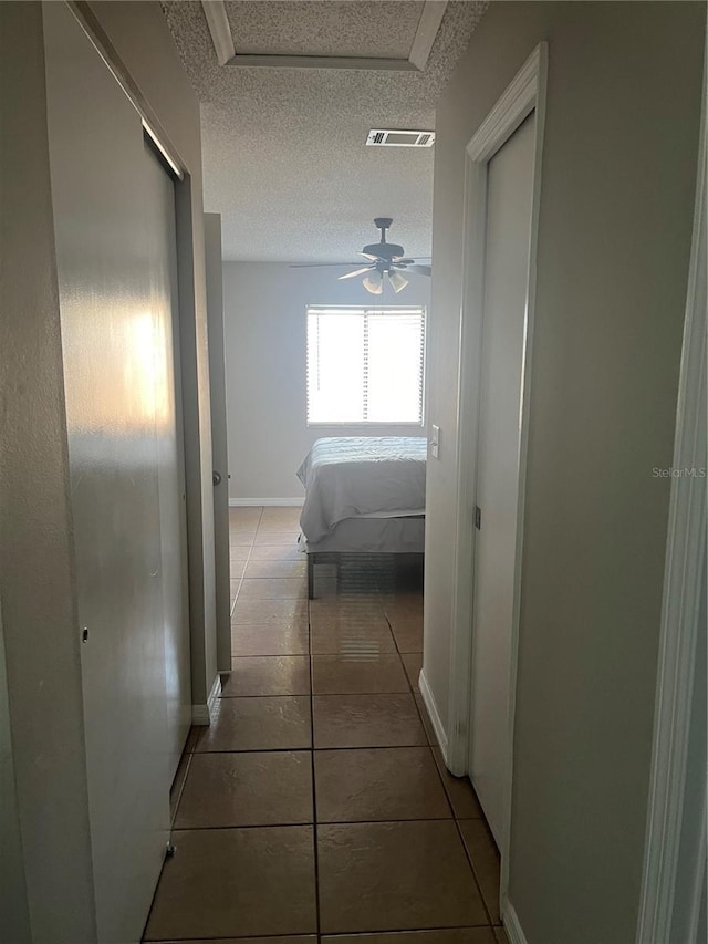 hall with tile patterned flooring and a textured ceiling