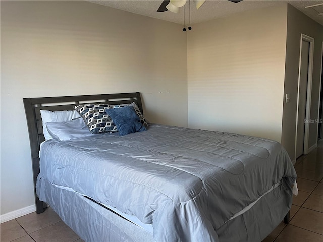 tiled bedroom with ceiling fan and a textured ceiling