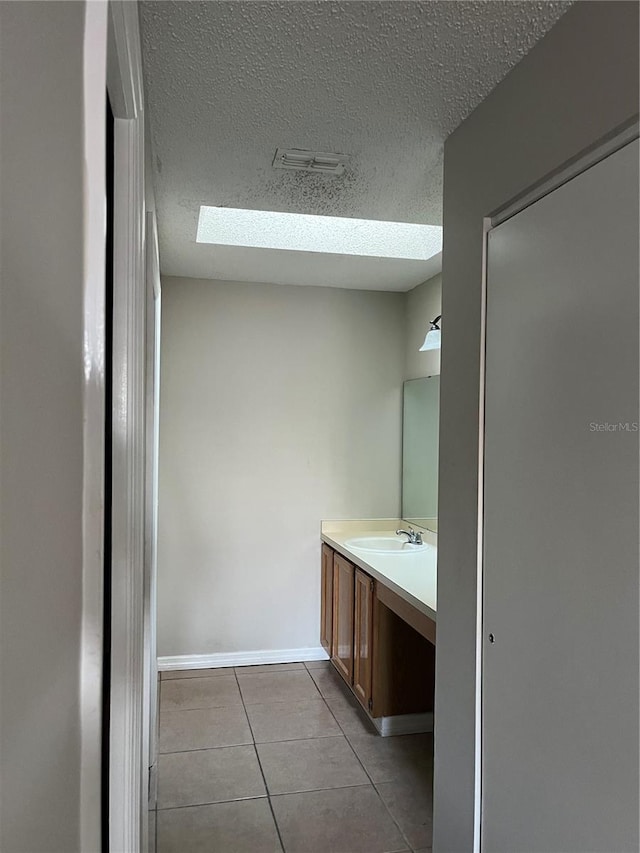 bathroom with vanity, a skylight, tile patterned flooring, and a textured ceiling