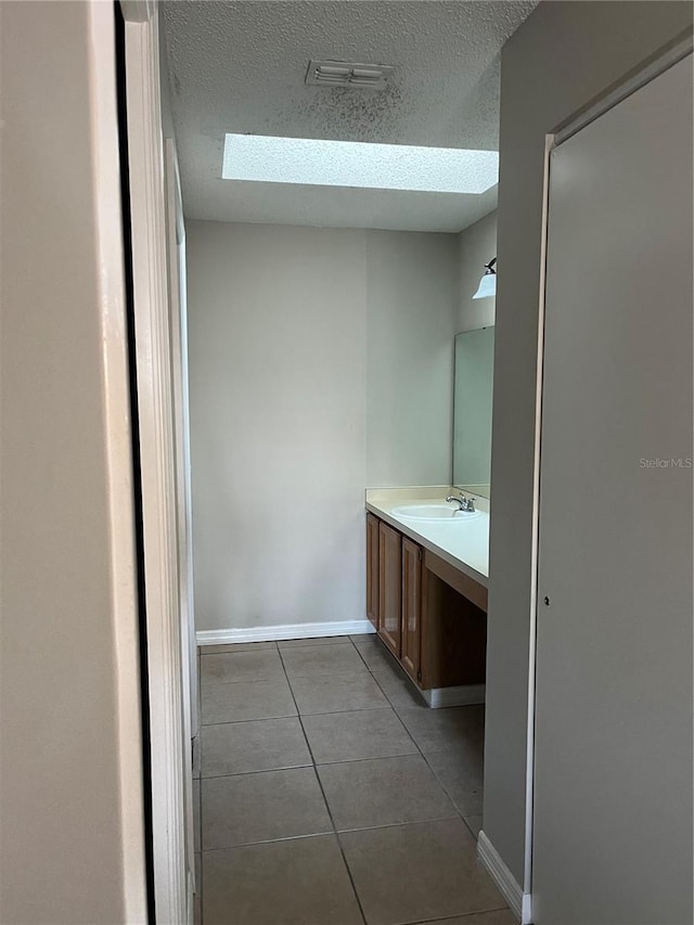 bathroom featuring vanity, a skylight, tile patterned flooring, and a textured ceiling