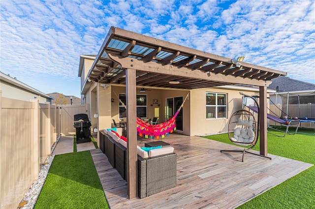 wooden deck featuring a trampoline, a yard, grilling area, a pergola, and an outdoor living space