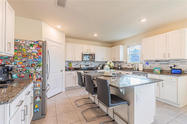 kitchen with stainless steel appliances, dark stone countertops, and white cabinets