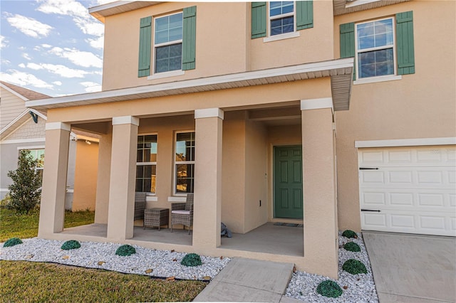 view of exterior entry with a garage and a porch