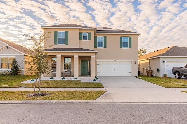 view of front of house featuring a garage, covered porch, a front lawn, and solar panels