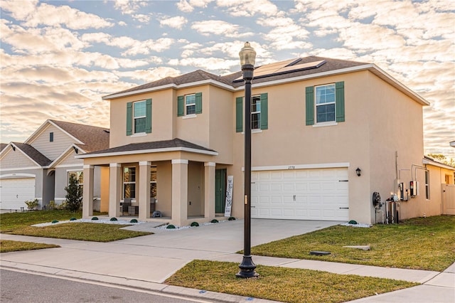 view of front of property with a garage, a yard, and solar panels