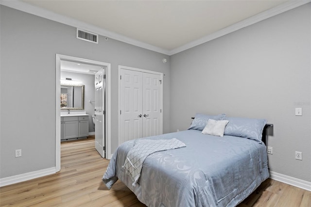 bedroom featuring ensuite bathroom, crown molding, light hardwood / wood-style floors, and a closet