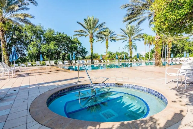 view of swimming pool with a hot tub and a patio area