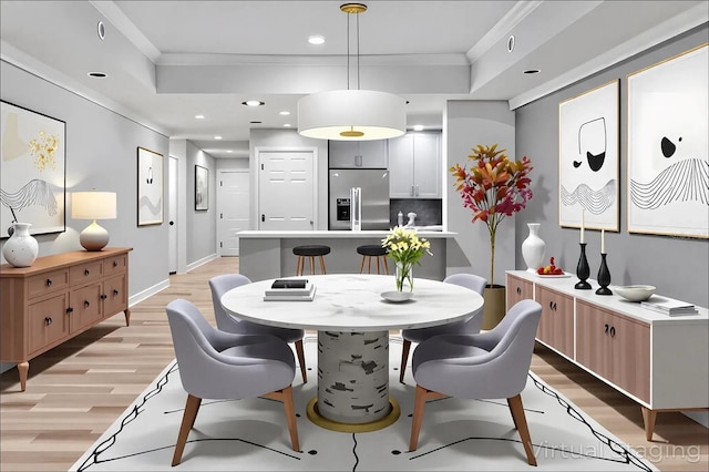 dining room featuring crown molding, light wood finished floors, and a tray ceiling