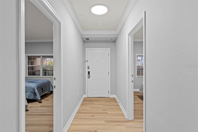 corridor featuring crown molding, visible vents, baseboards, and light wood-type flooring