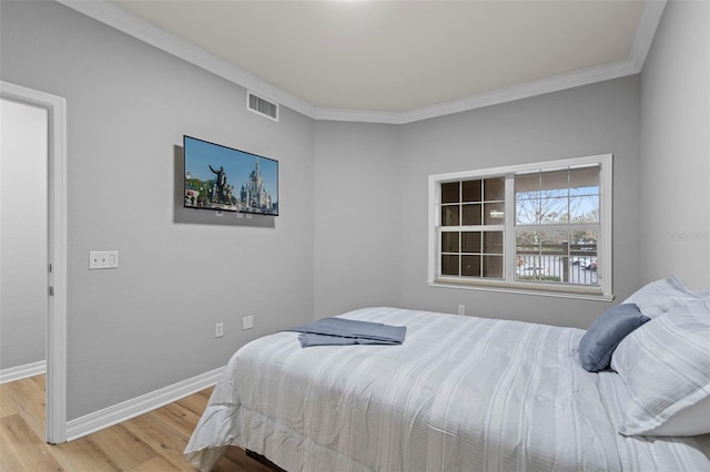 bedroom featuring ornamental molding, visible vents, light wood-style flooring, and baseboards