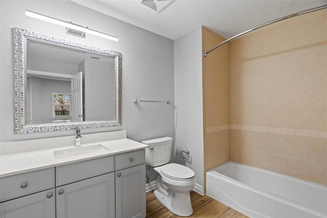 full bathroom with visible vents, shower / bathtub combination, toilet, wood finished floors, and vanity