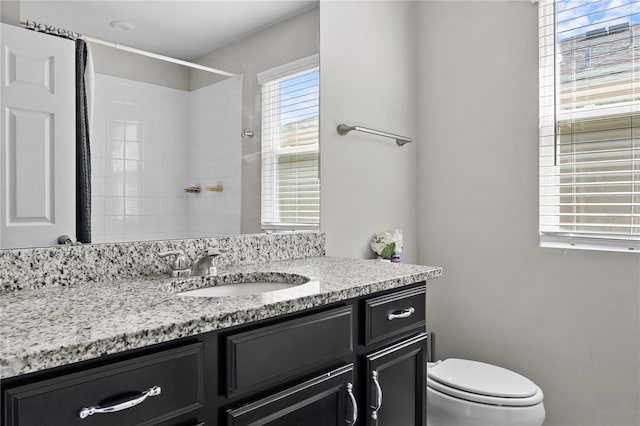 bathroom featuring toilet, walk in shower, and vanity