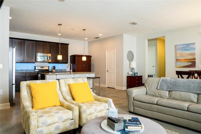 living room featuring concrete flooring, sink, and a textured ceiling