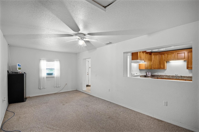 empty room with light colored carpet, a textured ceiling, and ceiling fan