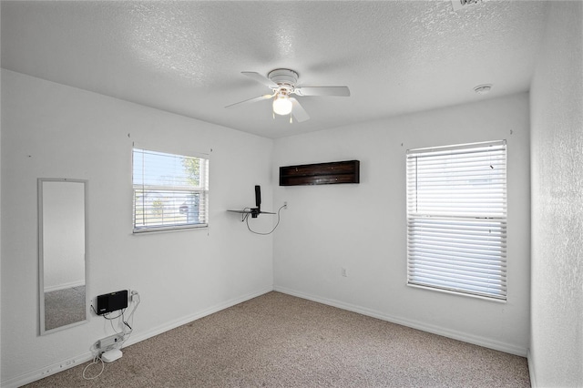 empty room with ceiling fan, carpet flooring, and a textured ceiling