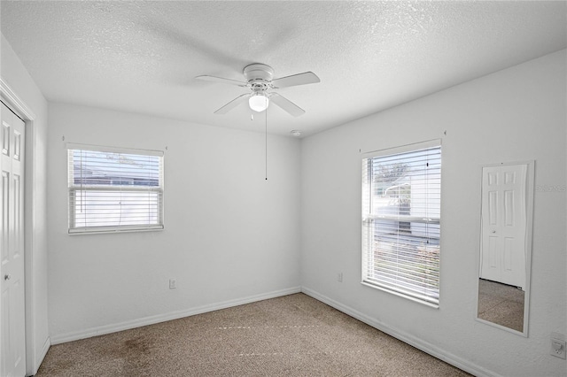 carpeted empty room with ceiling fan and a textured ceiling