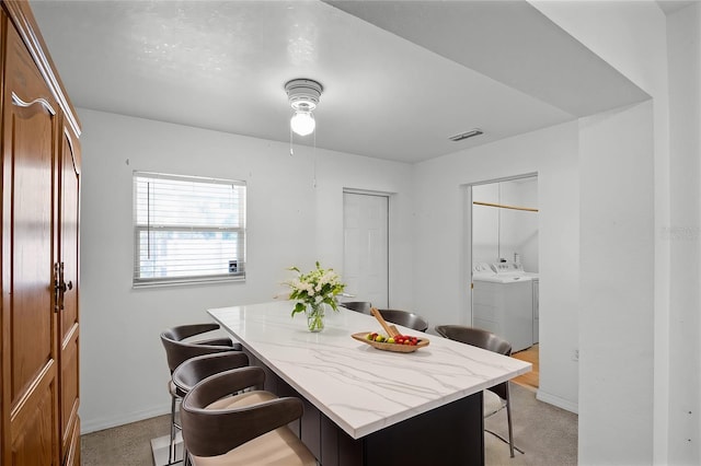 dining space featuring washing machine and dryer and light carpet