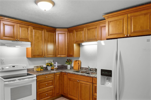 kitchen featuring sink, dark stone countertops, and white appliances