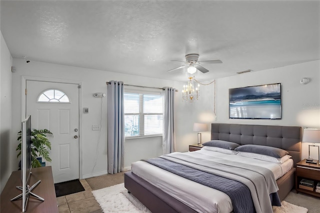 bedroom with ceiling fan with notable chandelier, a textured ceiling, and light tile patterned floors