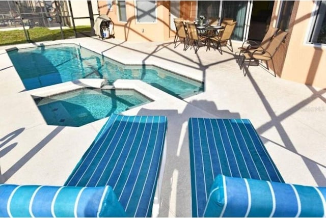 view of pool featuring an in ground hot tub, glass enclosure, and a patio