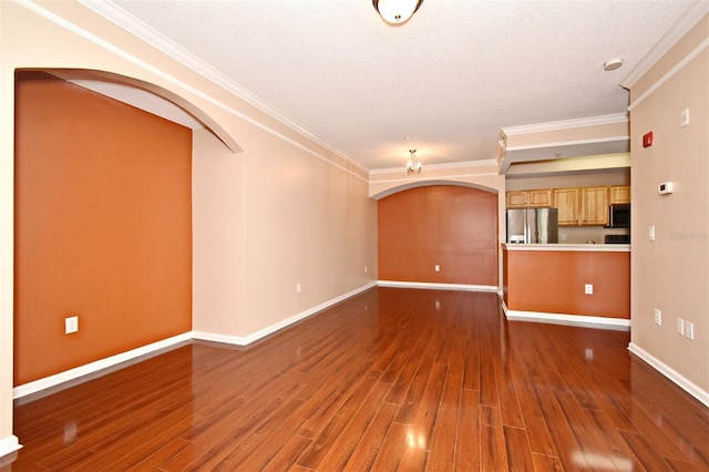 unfurnished living room featuring crown molding, dark wood-type flooring, and a textured ceiling