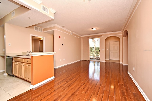 unfurnished living room with crown molding, sink, hardwood / wood-style flooring, and a textured ceiling