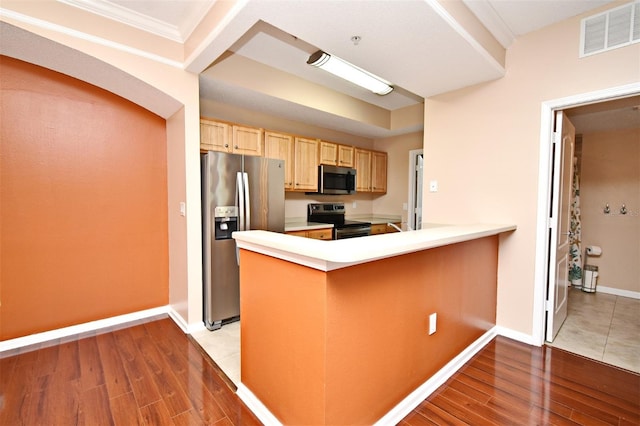 kitchen with stainless steel appliances, light brown cabinetry, light hardwood / wood-style floors, and kitchen peninsula