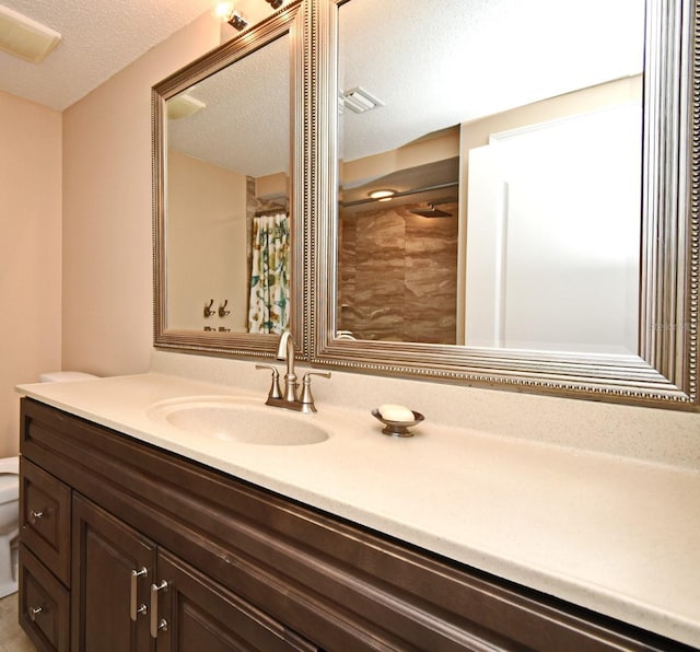 bathroom featuring a shower with curtain, vanity, a textured ceiling, and toilet