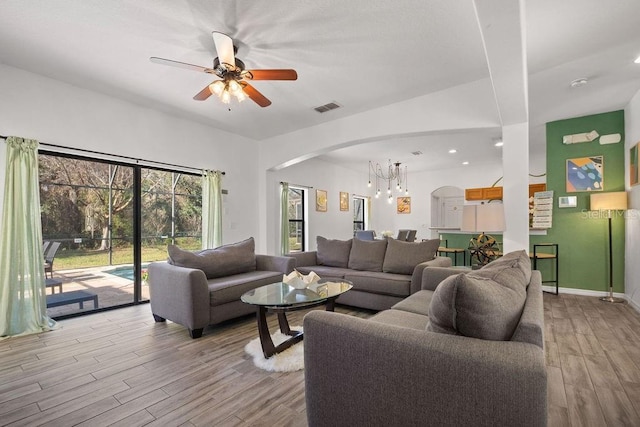 living room with ceiling fan with notable chandelier and light hardwood / wood-style flooring