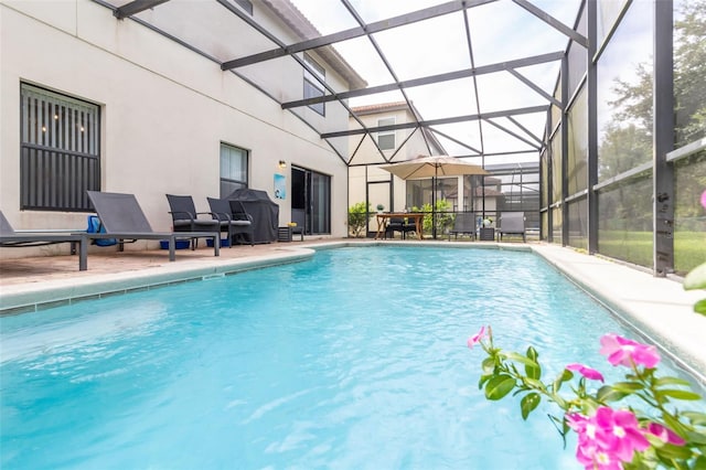 view of swimming pool with area for grilling, glass enclosure, and a patio area