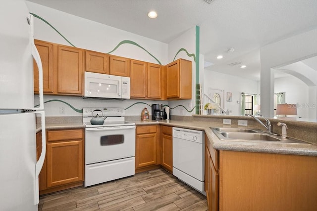 kitchen with white appliances, kitchen peninsula, sink, and light hardwood / wood-style flooring