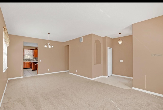 unfurnished room with light colored carpet and a chandelier