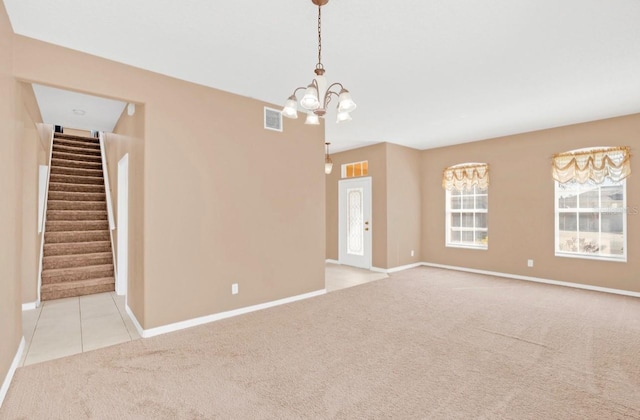 carpeted empty room featuring a notable chandelier