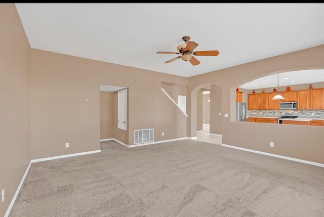 unfurnished living room with light colored carpet and ceiling fan