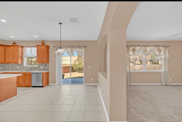 kitchen with tasteful backsplash, stainless steel dishwasher, hanging light fixtures, and light carpet