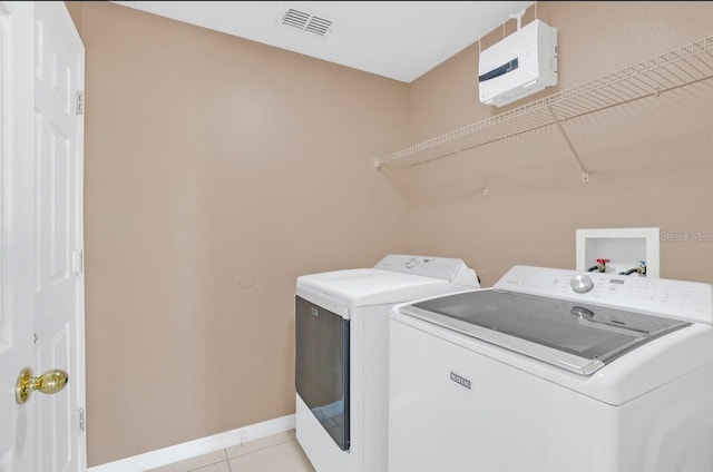 laundry area with light tile patterned floors and washer and clothes dryer