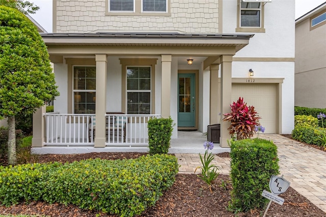 view of exterior entry with cooling unit, a porch, and a garage