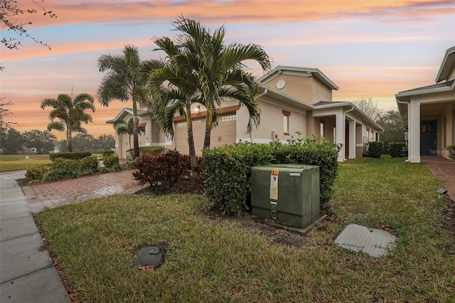 property exterior at dusk with a garage and a lawn